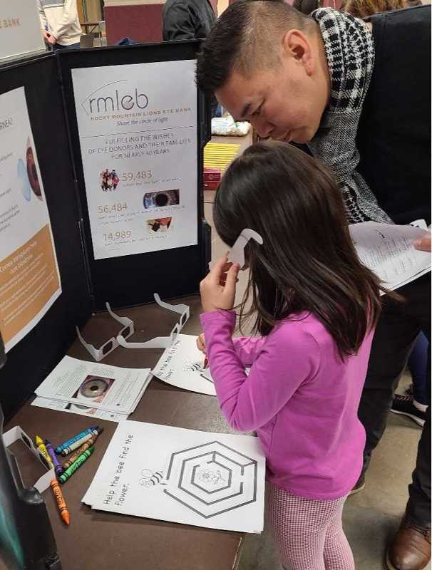 Photo of father and daughter trying on glasses that simulate blindness.